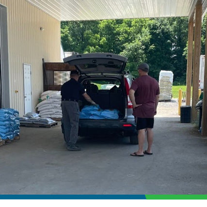 Store PickupTwo men loading supplies into the back of a vehicle at a store pickup area, with a large overhang providing shade.